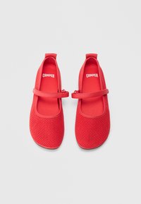 Zapatos de malla roja con punta redondeada y plana, con una correa sobre el empeine. Textura suave y plantillas con la marca "CAMPER".