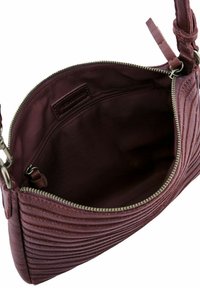 Sac en cuir bordeaux avec texture matelassée, fermeture éclair et doublure en coton. L'intérieur comprend une petite poche zippée et une étiquette en tissu.