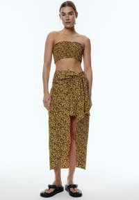 Geel luipaardmotief tweedelige set met een strapless top en een maxi-rok met een zijsplit en een gestrikt middel. Soepele stoftextuur.