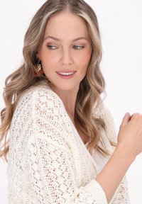 Cardigan in maglia color avorio con un motivo a maglia aperta, polsini a costine e vestibilità comoda. Presenta maniche lunghe e dettagli testurizzati.