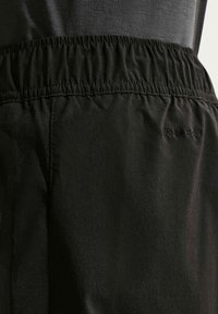 Λεπτομέρεια ζώνης μέσης μαύρου αθλητικού σορτς με ελαστική ταινία και διακριτικό κέντημα με το κείμενο "DRI-FIT" στο ύφασμα.