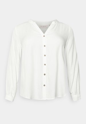 Blusa bianca a maniche lunghe con colletto alla mandarina, chiusura frontale con bottoni e maniche con polsini su uno sfondo grigio chiaro.