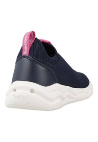 Zapatilla de punto azul marino con talón de goma y tejido texturizado. Cuenta con un bucle de acento rosa y una suela blanca ondulada con agujeros de ventilación.