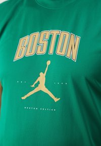 Groene katoenen T-shirt met "BOSTON" in vetgedrukte gele tekst en een gouden silhouet van een springende figuur, met "EST. 1946" en "BOSTON CELTICS" daaronder.