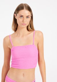Ružový crop top s tenkými ramienkami, ktorý má štruktúrovanú látku a smockovaný dizajn pre priliehavý vzhľad.