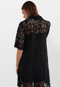 Rochie neagră din dantelă, cu mâneci scurte și guler. Model floral transparent, lungime până la genunchi, textură moale și detaliu cu spatele deschis.