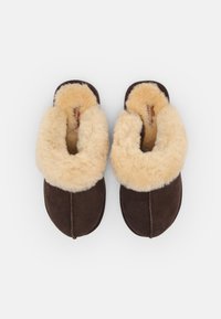 Brune suedette tøfler med en kremet ullinnside og mansjett. Glatt ytterside med stikkingdetaljer. Bred åpning for enkel påkledning.