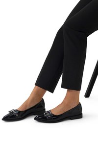 Zwarte lakleren ballerina's met een puntige neus, voorzien van een decoratieve hardwaregesp aan de voorkant en een lage hak.