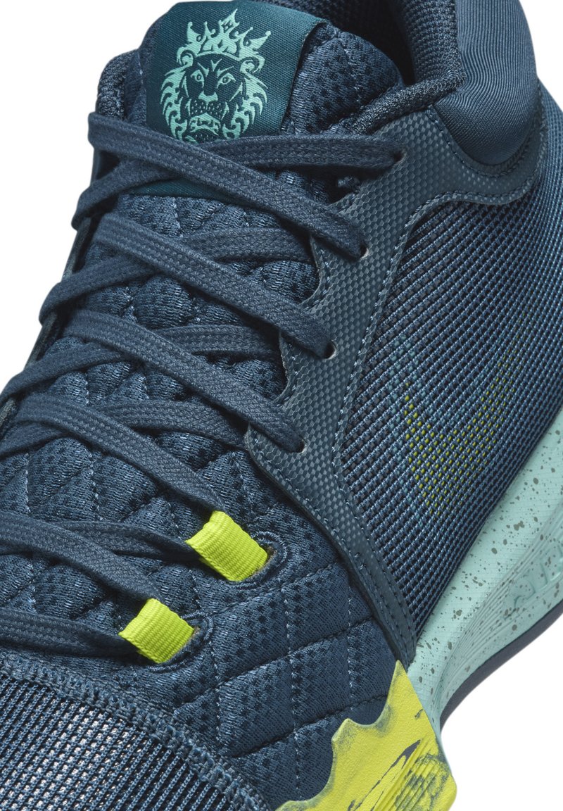 Dunkelblaue Sportschuhe mit oberem Material aus strukturiertem Netz, gelben Akzenten und gemusterter Sohle. Verfügt über aufwendige Nähte und auffällige Logodetails.