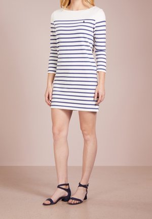 Striped dress in white and navy, featuring three-quarter sleeves and a silhouette just above the knee. Worn with navy heeled sandals.