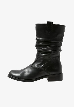 Czarne skórzane botki za kostkę z luźną cholewką, okrągłym noskiem i niskim obcasem w kształcie bloku. Gładka faktura i minimalne detale przeszyć.