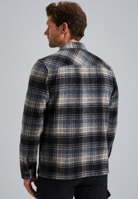 Miesten ruudullinen flanellipaita mustassa, valkoisessa ja sinisen sävyissä. Ominaisuuksiin kuuluu kaulus, napilliset hihanpäät ja tekstuuri, jossa on ruutukuvio.