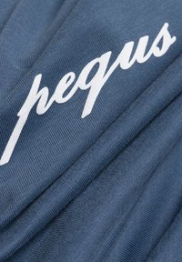 Blauer Stoff mit gerippter Textur, auf dem in geschwungener weißer Schrift "pequs" über die Oberfläche geschrieben steht. Die Falten erzeugen sanfte Schatten.