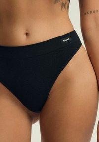 Czarne, prążkowane majtki bikini o niskim stanie z płaskim pasem i małą metką marki z boku. Miękki, elastyczny materiał.