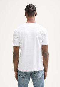 Hvid bomulds T-shirt med korte ærmer, rund hals, glat tekstur og en afslappet pasform, vist fra ryggen mod en neutral baggrund.