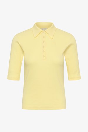 Ανοιχτό κίτρινο πόλο με κοντά μανίκια, μυτερό γιακά, έξι κουμπιά μπροστά και διακριτικό ανάγλυφο λογότυπο στο στήθος.