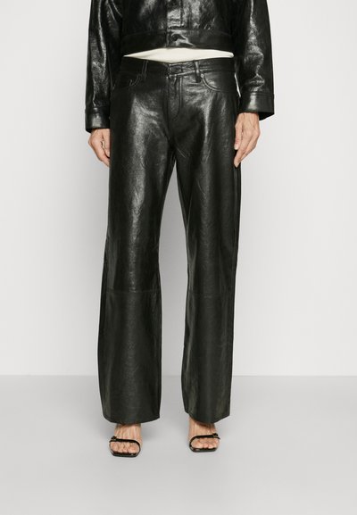 Black leather wide-leg trousers with a smooth texture, featuring a high waistband and subtle stitching details, paired with black strappy sandals.