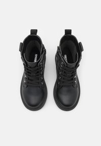 Botas de tobillo de cuero negro con superficie texturizada, punta redonda, parte delantera con cordones y cierre de cremallera. Cuenta con una lengüeta en la parte posterior.