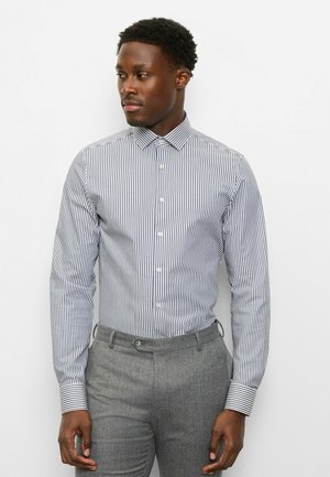 Striped button-up shirt in blue and white, with a spread collar and long sleeves, paired with gray tailored trousers.