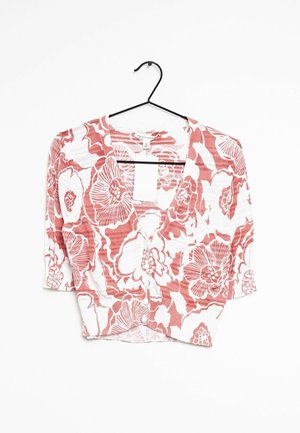 Chemisier à manches courtes boutonné avec motif floral corail et blanc suspendu sur un cintre noir sur fond blanc.
