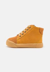 Gule semsket høye sneakers med en teksturert tåhette, forsterket hæl og beige snørebånd; har kontrastfarget søm og gummisåle.
