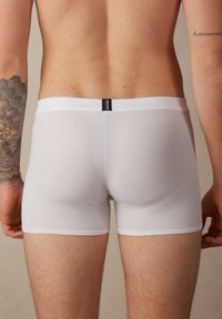 Vita bomullsboxershorts med en mjuk midja och en svart etikett. Plagget är åtsittande och slätt, vilket ökar komforten och ger en strömlinjeformad siluett.