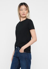 Zwarte katoenen T-shirt met korte mouwen en een ronde hals, gecombineerd met donkerblauwe denimjeans. Eenvoudig, aansluitend ontwerp zonder patronen.