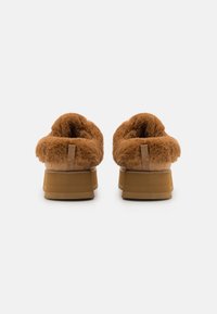 Brune plattformstøvler med en fluffy pelskrage, mykt innvendig og en robust beige såle. Bak har de en liten stoffsløyfe for enkel påkledning.