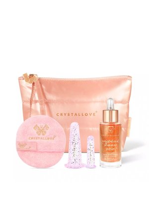 Różowy kosmetyczny woreczek Crystallove z rozświetlającym serem, dwiema fioletowymi kubeczkami do masażu twarzy oraz okrągłym różowym płatkiem do demakijażu.