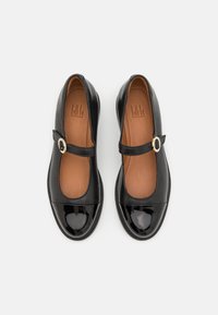 Zwarte gepatineerde leren Mary Jane-schoenen met een ronde neus, platte zool en een gespband over de wreef. Bruine binnenvoering.