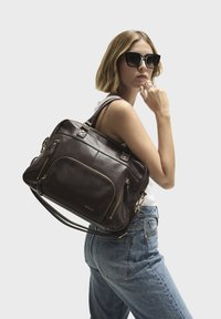 Ciemnobrunatna skórzana torba na ramię z wieloma zamykanymi na zamek kieszeniami, akcentami w kolorze złotym oraz podwójnymi paskami na ramię. Gładka faktura i sztywny kształt.