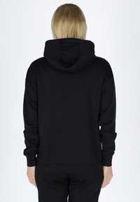 Black hooded sweatshirt made of soft fabric, features a relaxed fit, ribbed cuffs, and hem with a smooth, plain texture.