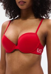 Ερυθρός καλουπωμένος σουτιέν με ρυθμιζόμενες τιράντες, λεία υφή και λεπτομέρεια με λογότυπο. Διαθέτει στηρίγματα με μπανέλα και κλασικό σχεδιασμό για άνεση.