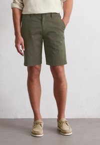 Shorts vert olive en tissu léger, dotés d'un devant plat, de deux poches latérales et d'un ourlet roulé pour une finition soignée.