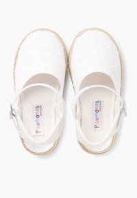 Zapatillas de lona blancas con bordado floral, punteras redondas y correas en el tobillo ajustables; suelas tipo yute que añaden textura y contraste.