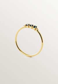 Anillo de oro con una banda delgada, que presenta cinco piedras preciosas azules engastadas en un ajuste de garras, creando un diseño agrupado. Acabado suave y brillante.