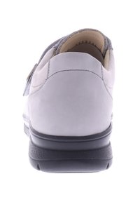 Gray suede shoe with a thick black sole, featuring a rounded heel and a soft interior lining. Strap closure detail is visible on the side.