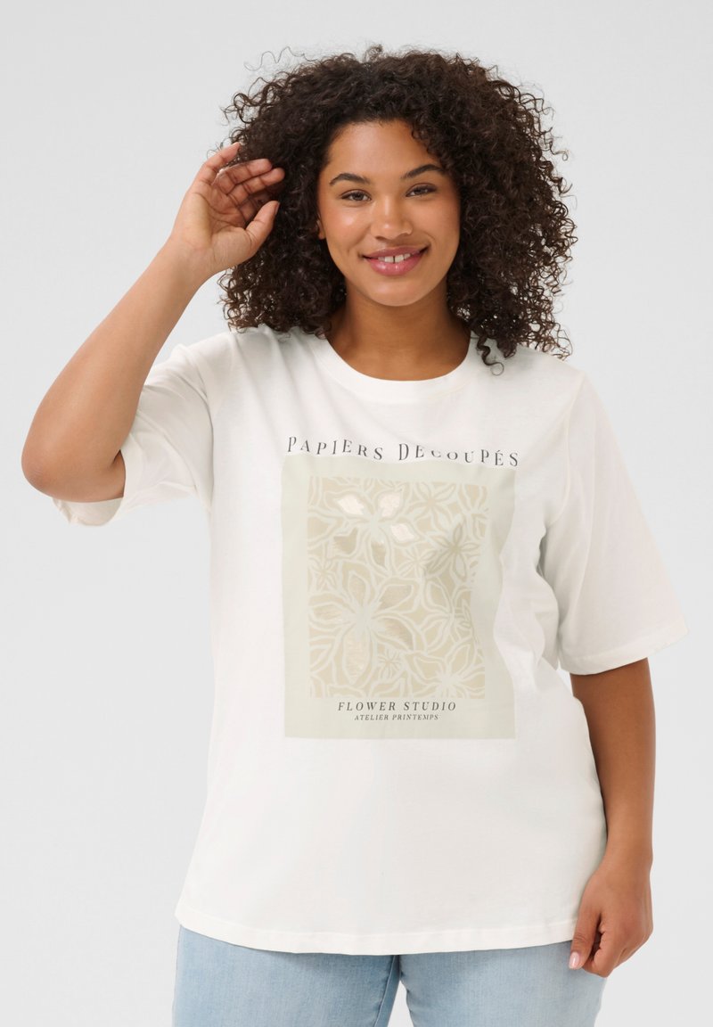 T-shirt en coton blanc à manches courtes, avec un motif floral beige et du texte sur le devant. Le tissu semble lisse et léger.