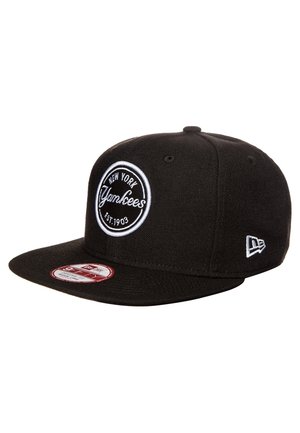 Casquette noire des New York Yankees avec logo brodé blanc et texte "Est. 1903", visière plate et emblème New Era sur le côté.