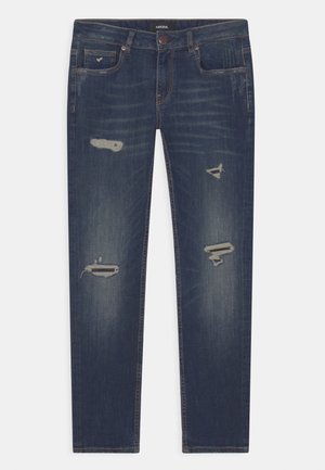 Dark blue denim jeans with distressed patches. Features five pockets, belt loops, and a straight-leg design. Classic button and zipper closure.