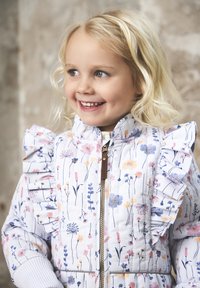 Veste rembourrée fleurie en blanc, avec des épaules froncées, une fermeture éclair sur le devant et de délicats motifs de fleurs roses, bleues et jaunes.
