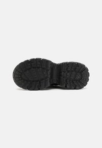 Black rubber shoe sole with deep treads and various patterns for traction. Smooth, matte finish suitable for outdoor use.