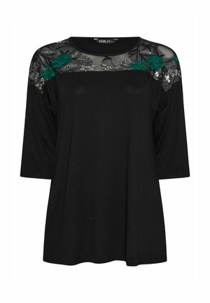 Top negro con mangas tres cuartos, bordado floral transparente en los hombros y un corte relajado. Fabricado con tela suave y con un escote redondo.