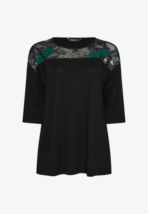 Zwarte top met driekwart mouwen, doorschijnende bloemenborduursels op de schouders en een relaxte pasvorm. Gemaakt van zachte stof met een ronde halslijn.