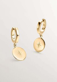 Pendientes de aro de oro que presentan un colgante redondo con un diseño de estallido de estrellas, acabado brillante y superficie lisa, colgando de un cierre seguro.
