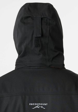 Giacca nera con cappuccio e superficie texturizzata, dotata di una manica in Velcro e un logo bianco "SWEDEMOUNT" sopra un grafico di montagna.