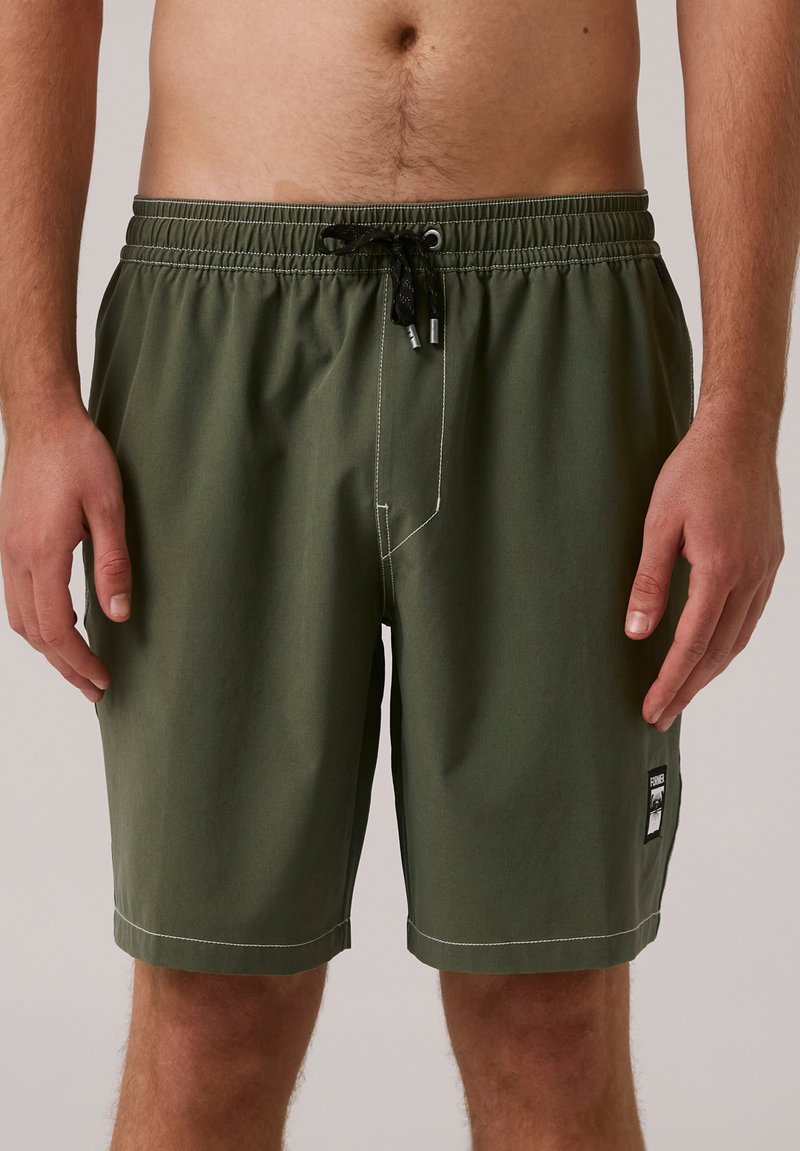 Shorts de bain vert olive avec une taille élastique, cordon de serrage ajustable, couture blanche et un patch logo sur le côté.
