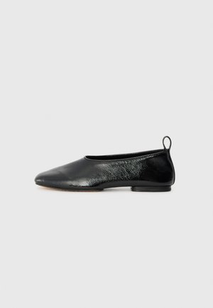 Ballerines noires en cuir lisse et texturé, à bout pointu, petit talon et une petite boucle arrière pour un enfilage facile.