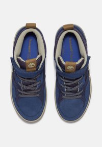 Baskets en daim bleu avec un intérieur beige, présentant des accents marron, des lacets ronds et une languette en tissu texturé. Design léger.