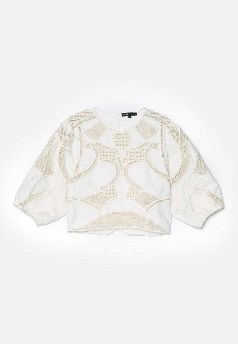 Haut court blanc présentant des motifs texturés complexes, y compris des mailles et des motifs géométriques, avec des manches bouffantes et un ourlet arrondi.